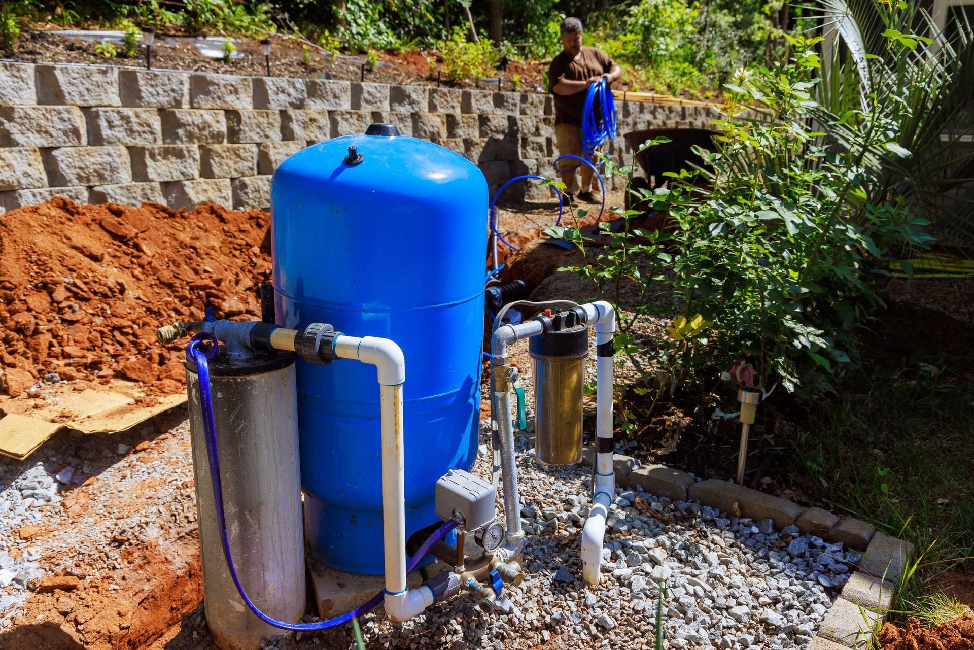 A man is standing next to a blue water tank.