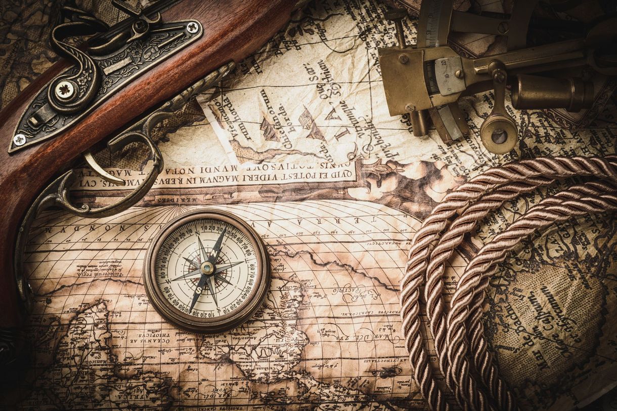 Antique compass and firearm on a vintage map with rope and brass instruments, brown tones.