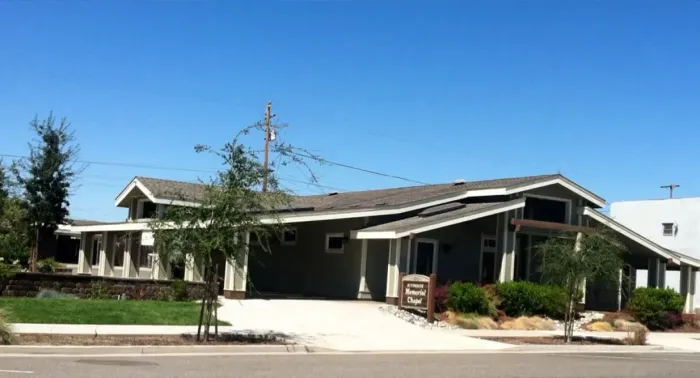 Single-story suburban house with a front porch, driveway, and small front yard on a sunny day