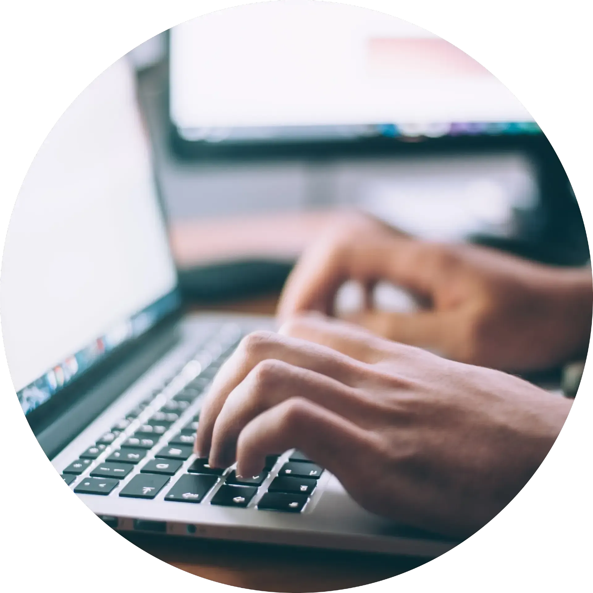 Hands typing on a laptop keyboard in a bright office setting