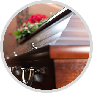 Polished brown casket with silver handles and red flowers, viewed in close-up.