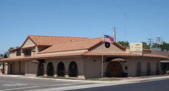 Spanish-style street corner building with terracotta roof, arches, and an American flag