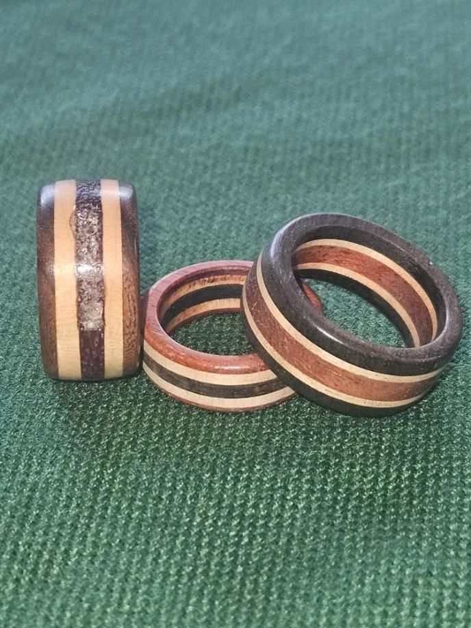 Three wooden rings with black and natural stripes on green fabric.