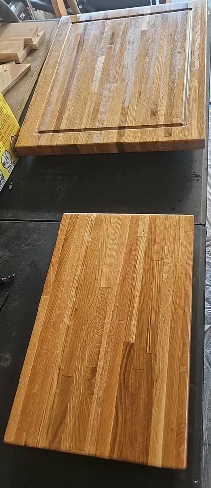 Two wooden cutting boards on a conveyor belt, one lighter and one darker.