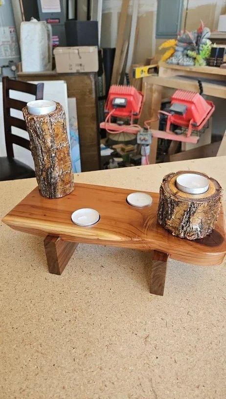 Wooden candle holder with two glass jars and tea lights on a bench in a workshop