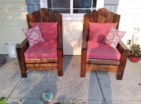Two wooden armchairs with pink cushions and patterned pillows on a front porch