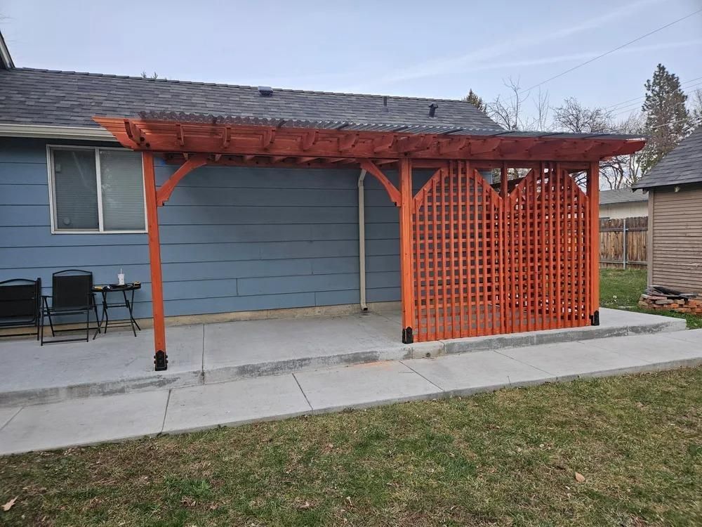 Orange pergola and lattice privacy screen on a concrete patio beside a blue house