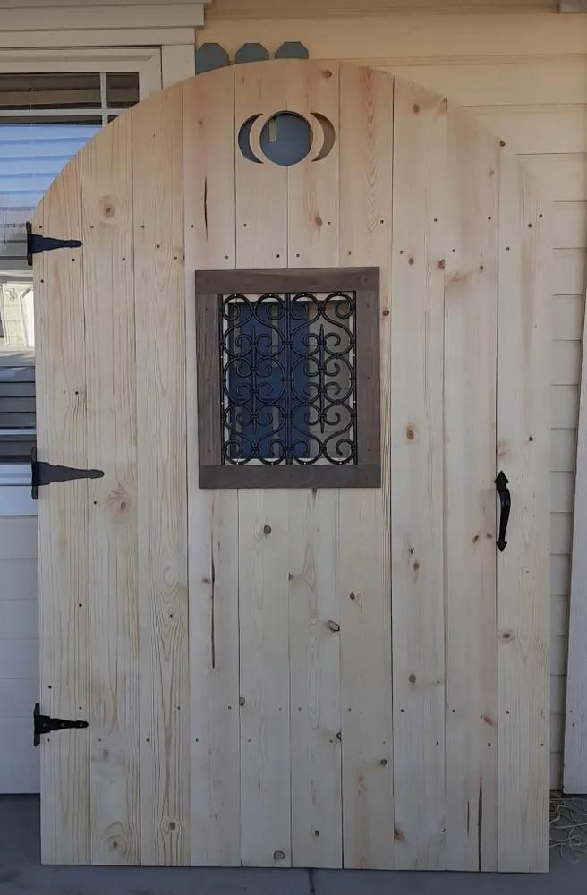 Wooden arched door with small barred window and iron hinges on a porch