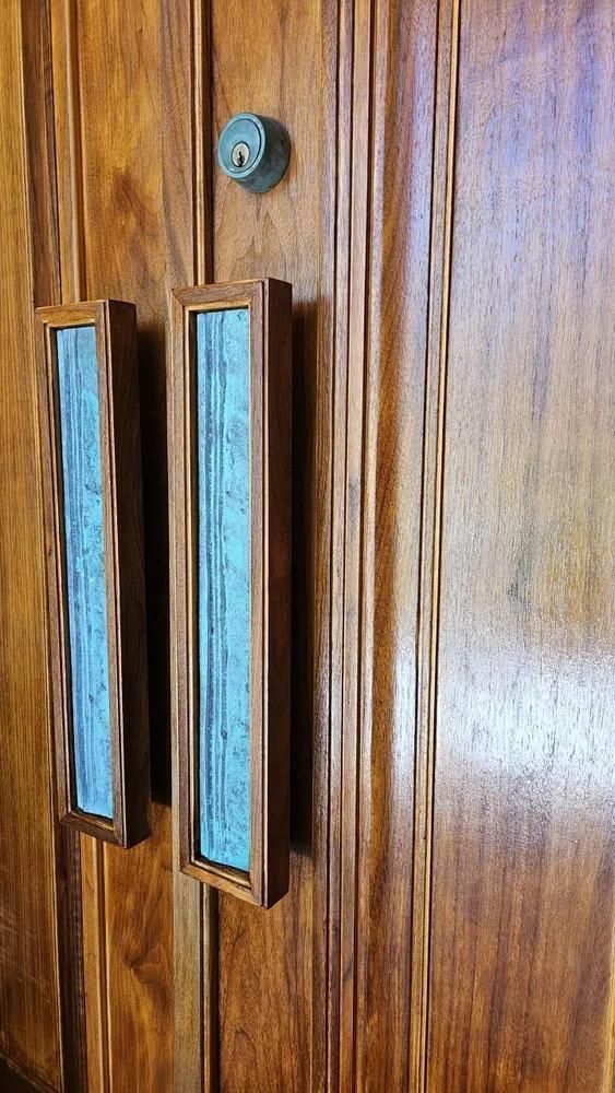 Wooden door with two vertical glass handles and a small round lock above them.