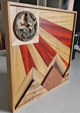 Wooden geometric art plaque with red and tan rays and a small circular medallion in the corner