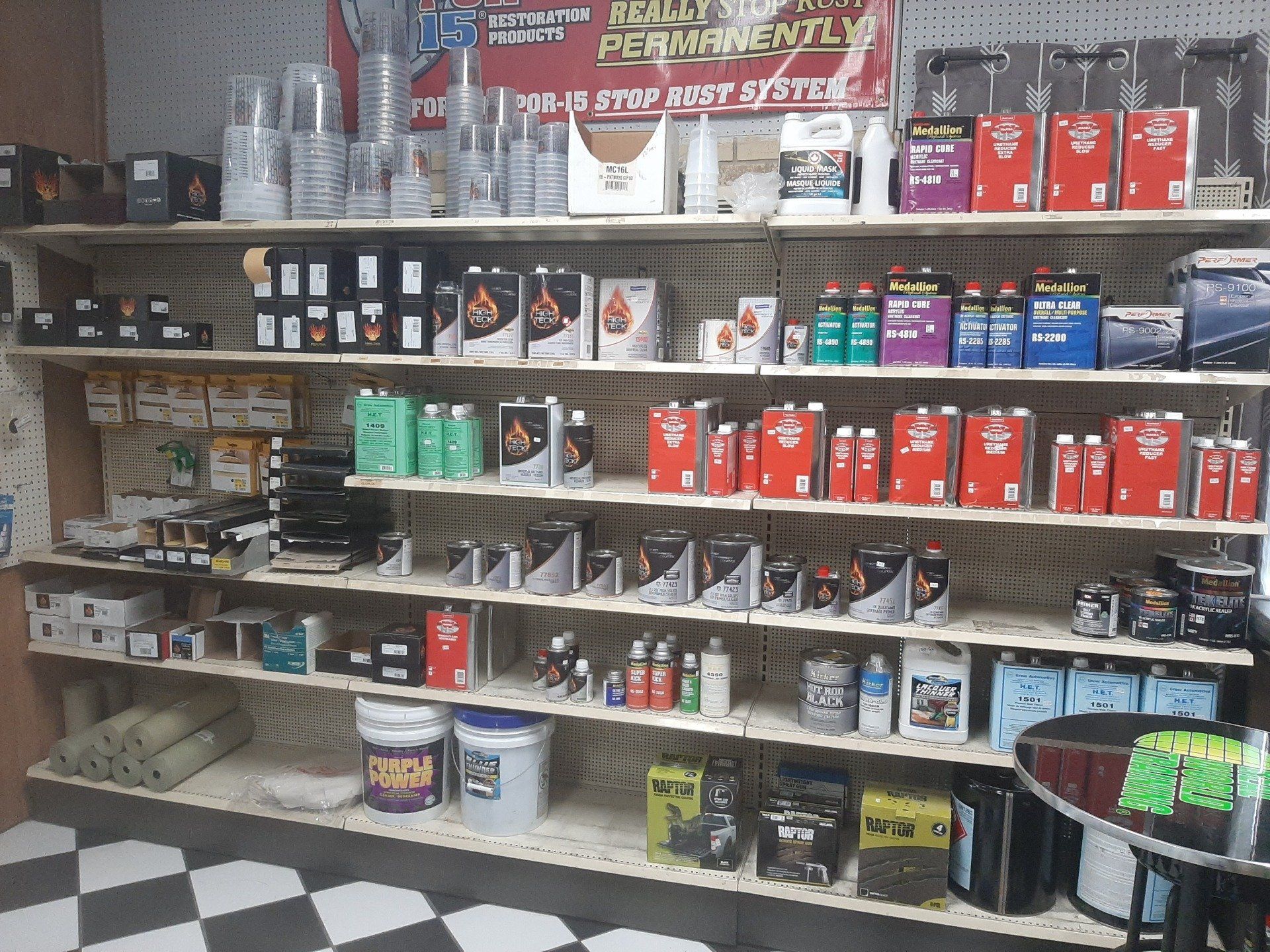 Shelved hardware store aisle with assorted paints, cleaners, and supplies in red, white, and green packaging
