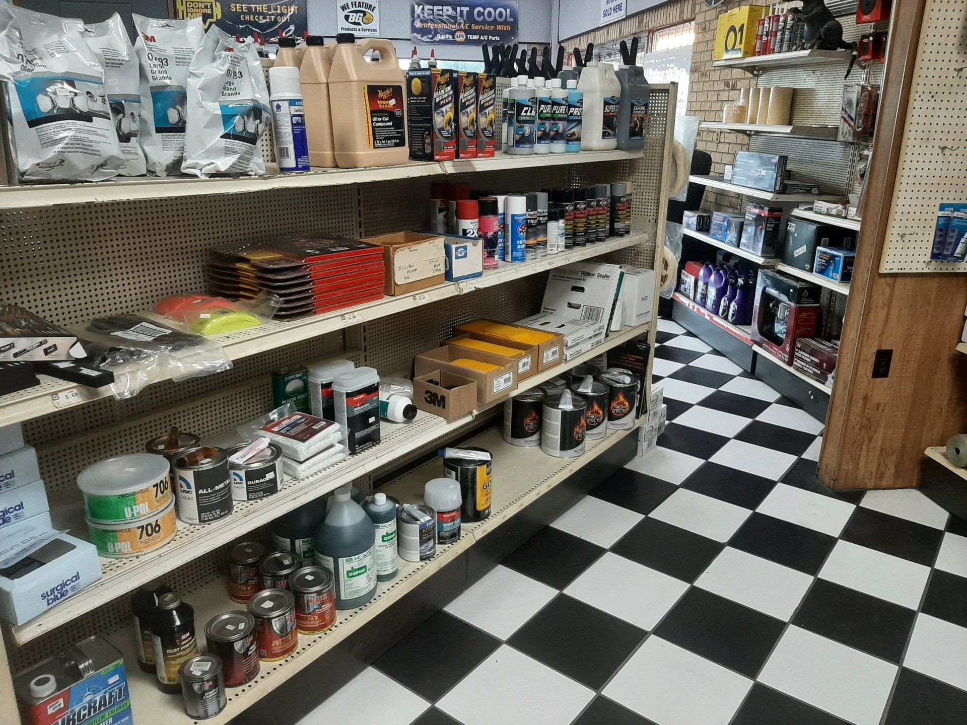 Pet supply store aisle with shelves of pet food, treats, and supplies on a black-and-white checkered floor
