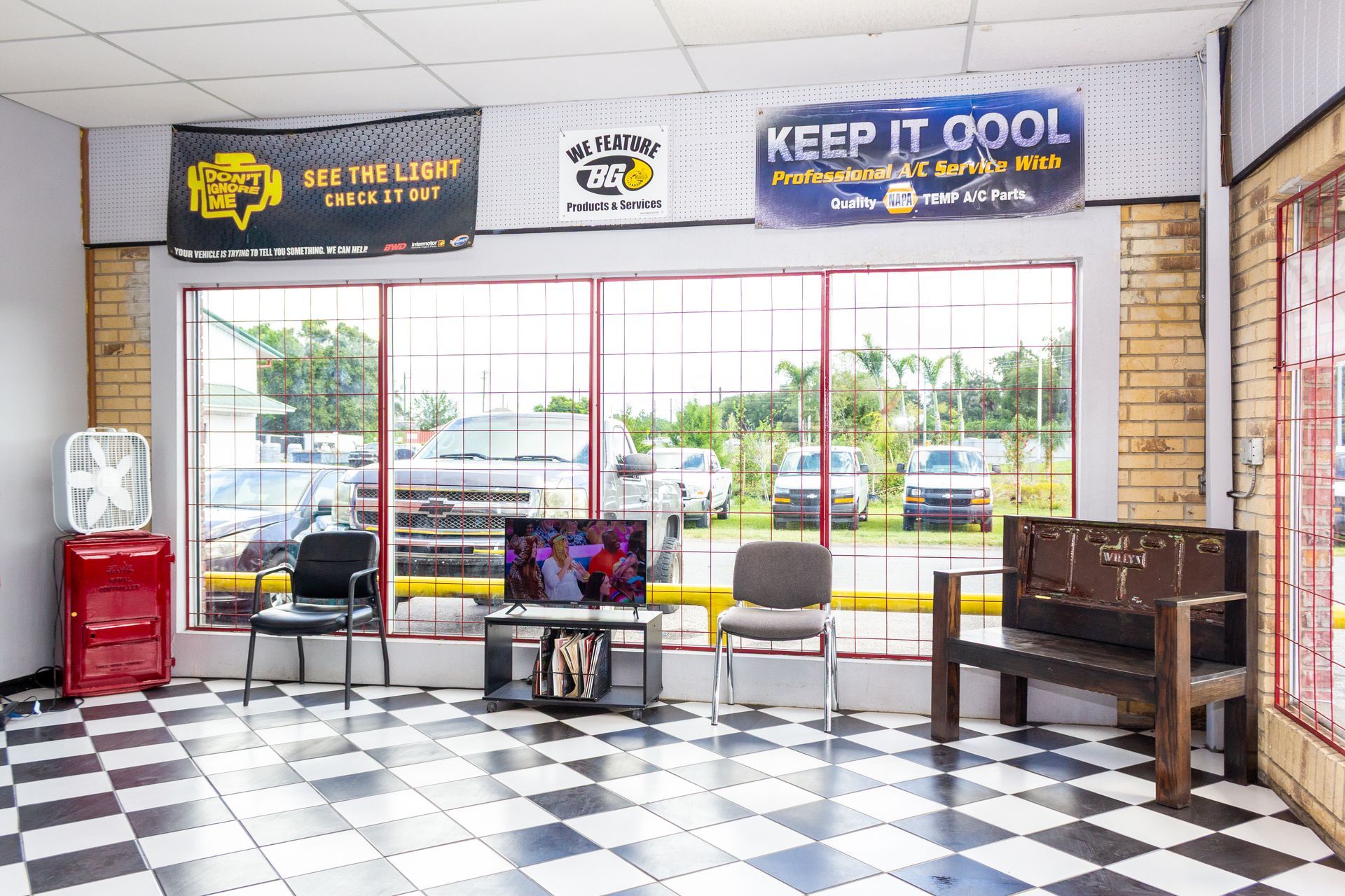 Empty storefront lobby with checkered floor, chairs, bench, and large front windows with signs above