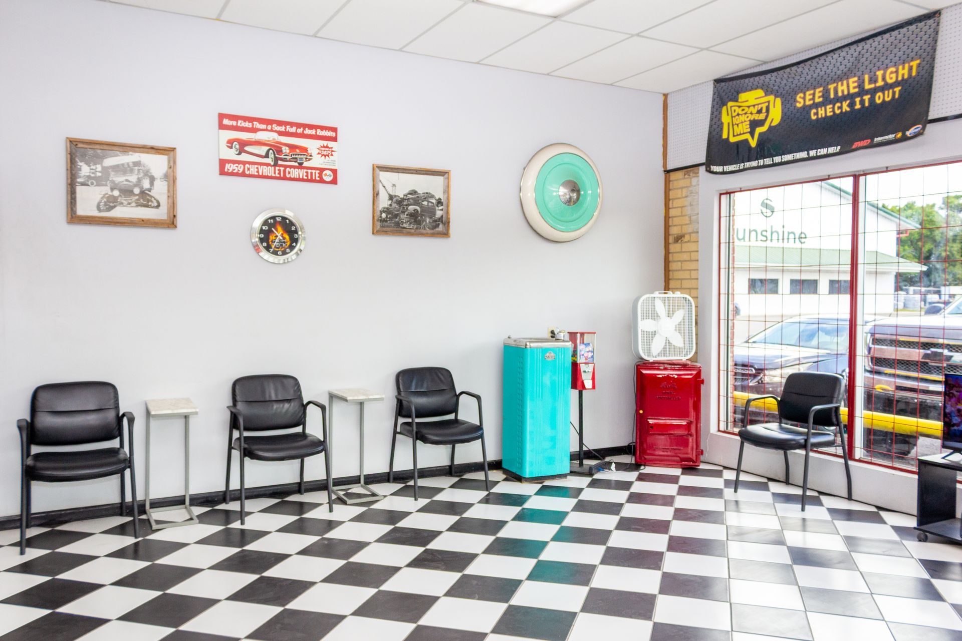 Waiting area with black chairs, checkered floor, turquoise and red coolers, and a glass entrance door