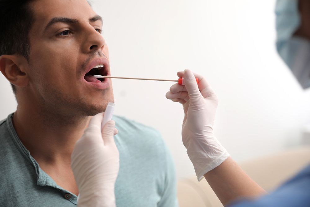 A man is getting a swab from his mouth.