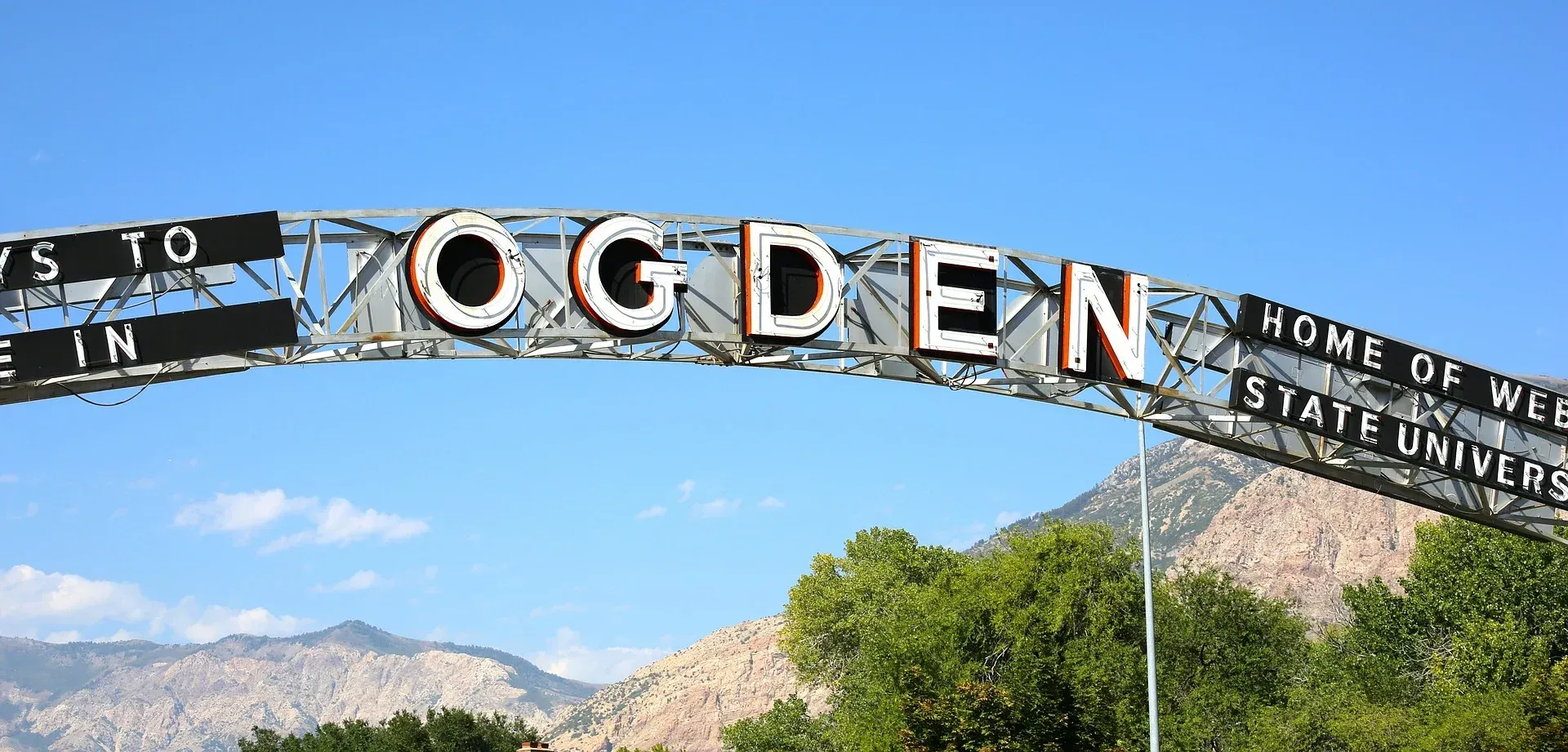 The word ogden is on a sign with mountains in the background