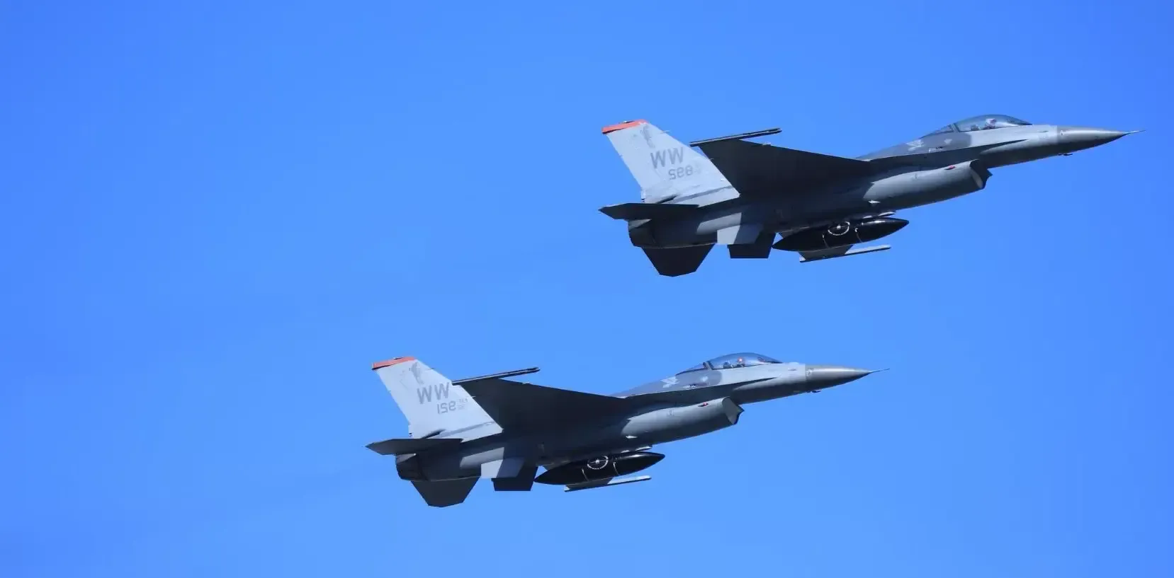 Two fighter jets are flying in formation in the sky.