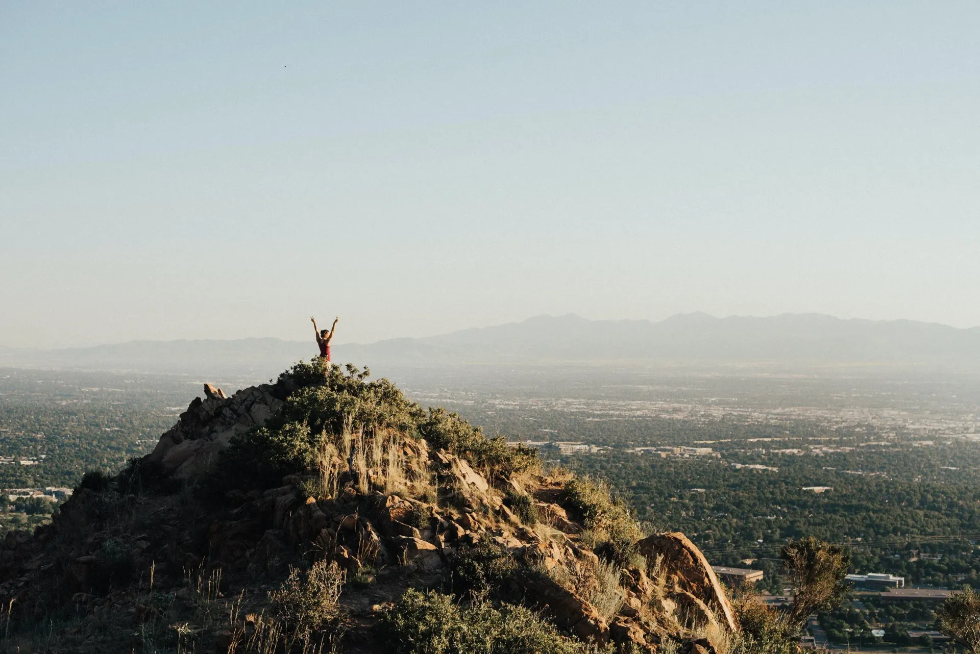 A person is standing on top of a hill overlooking a city.