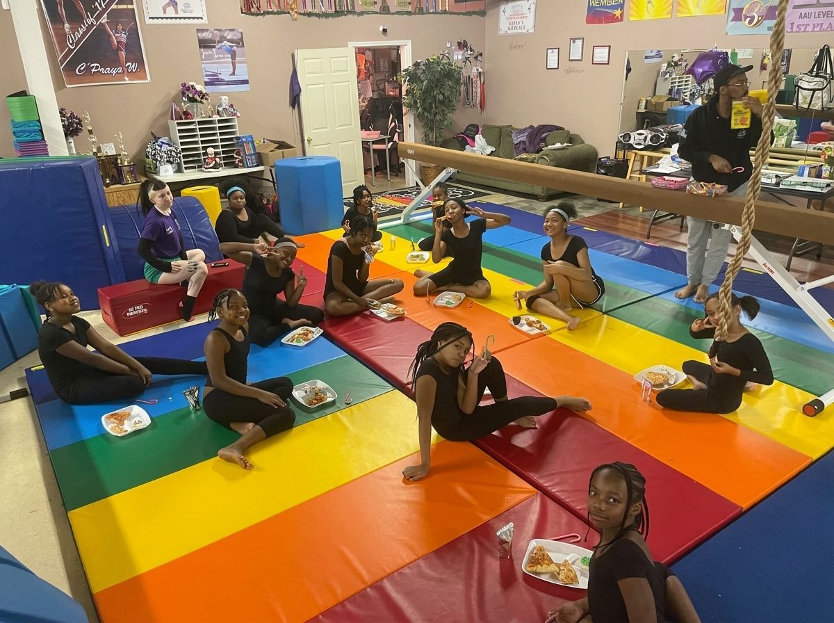 Gymnastics class stretching on blue mats in a large indoor gym.