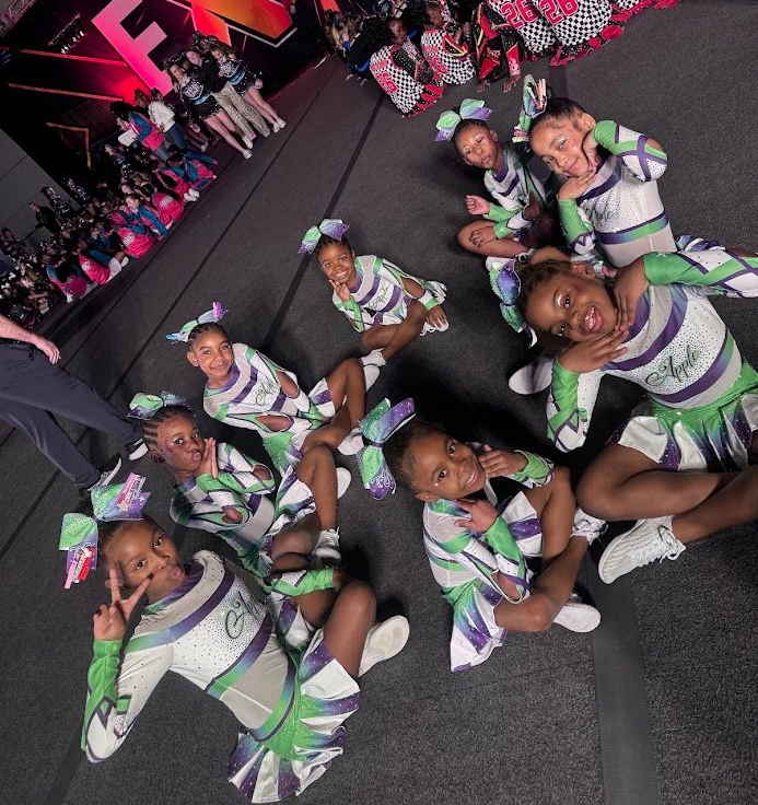 Seven people in white-and-green uniforms posing outdoors under a concrete overhang.