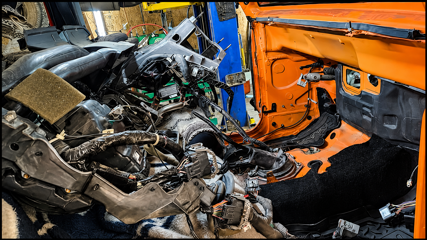 Severely damaged car interior with twisted metal, exposed engine parts, and orange body panels