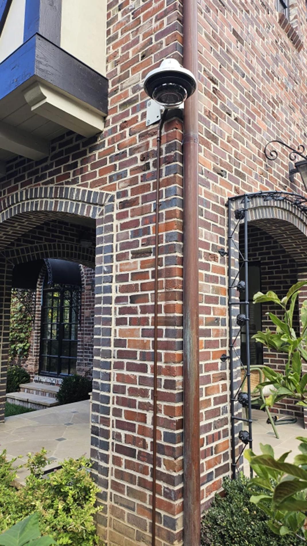 A security camera is mounted on the side of a brick building.