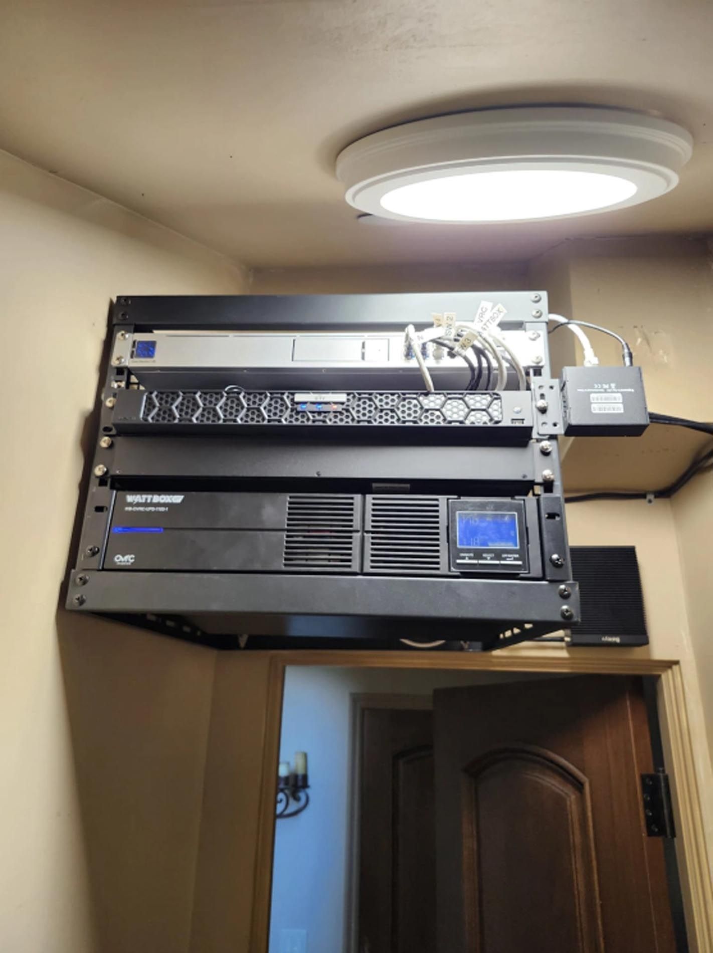 Network equipment mounted above a doorway in a room, with a ceiling light overhead