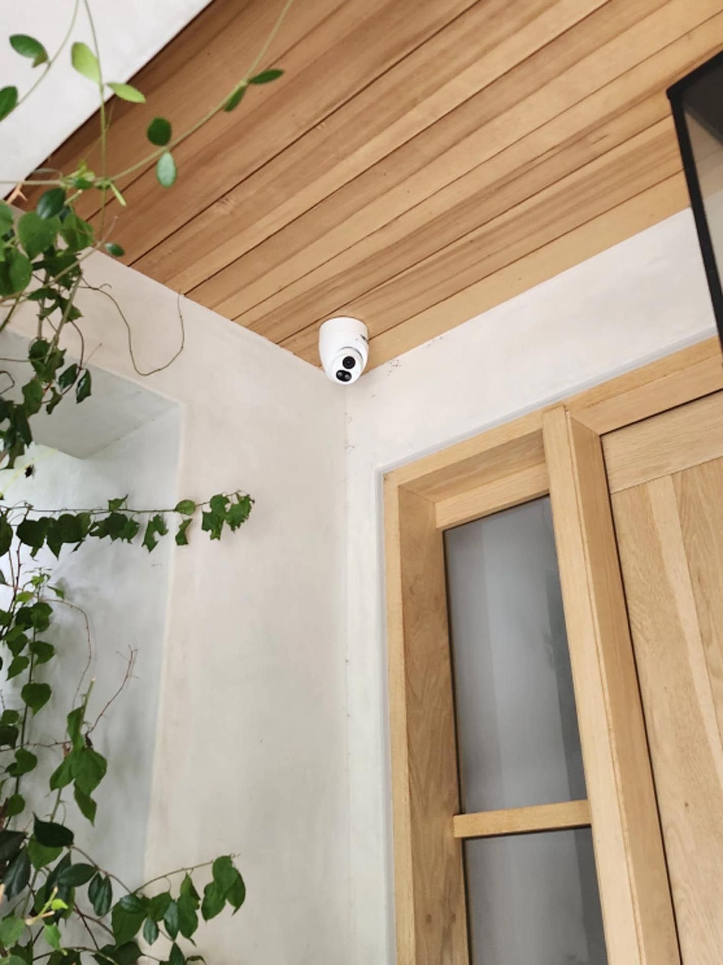 A security camera is hanging from the ceiling above a door