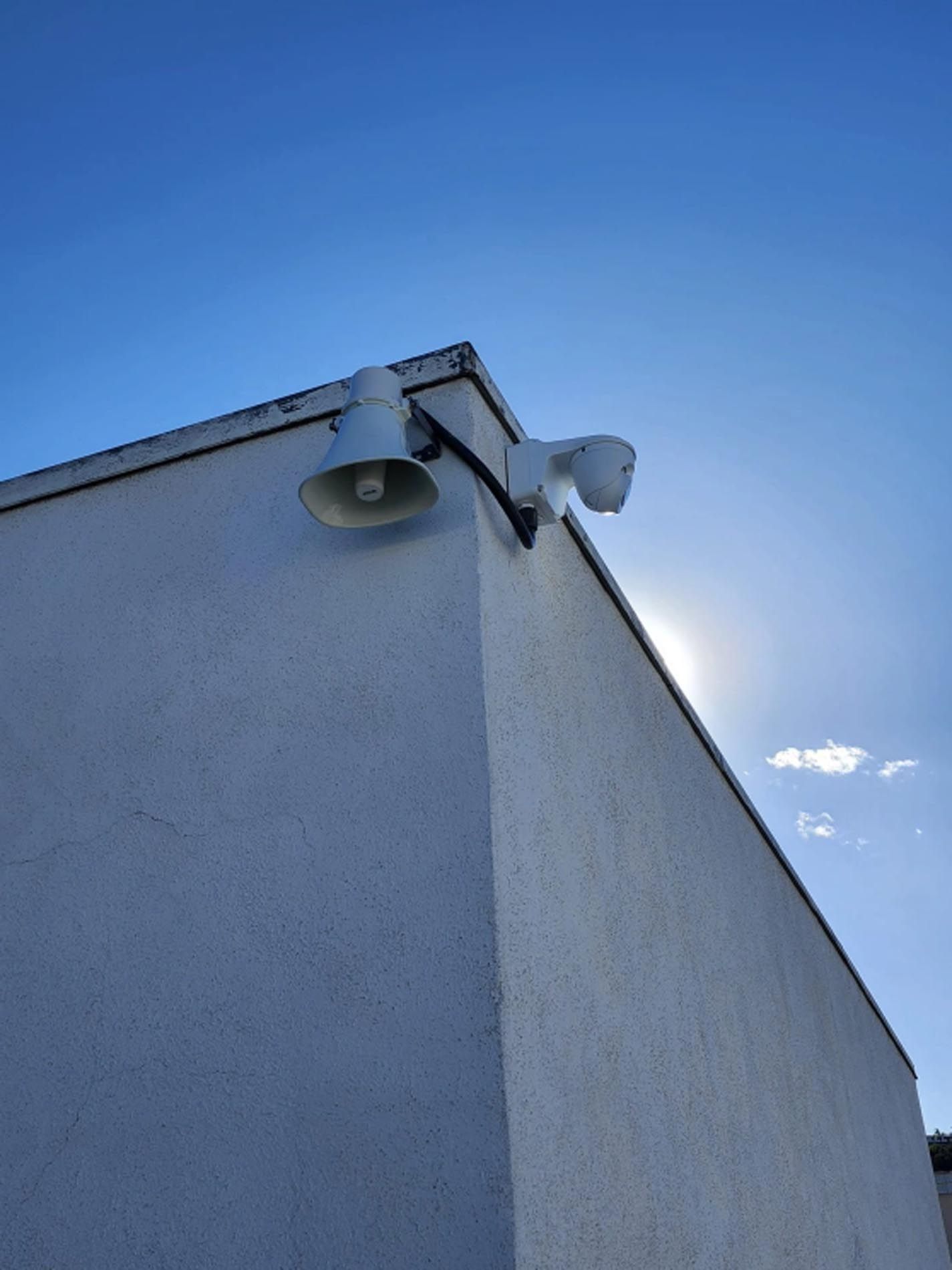 White building corner with security lights against a blue sky