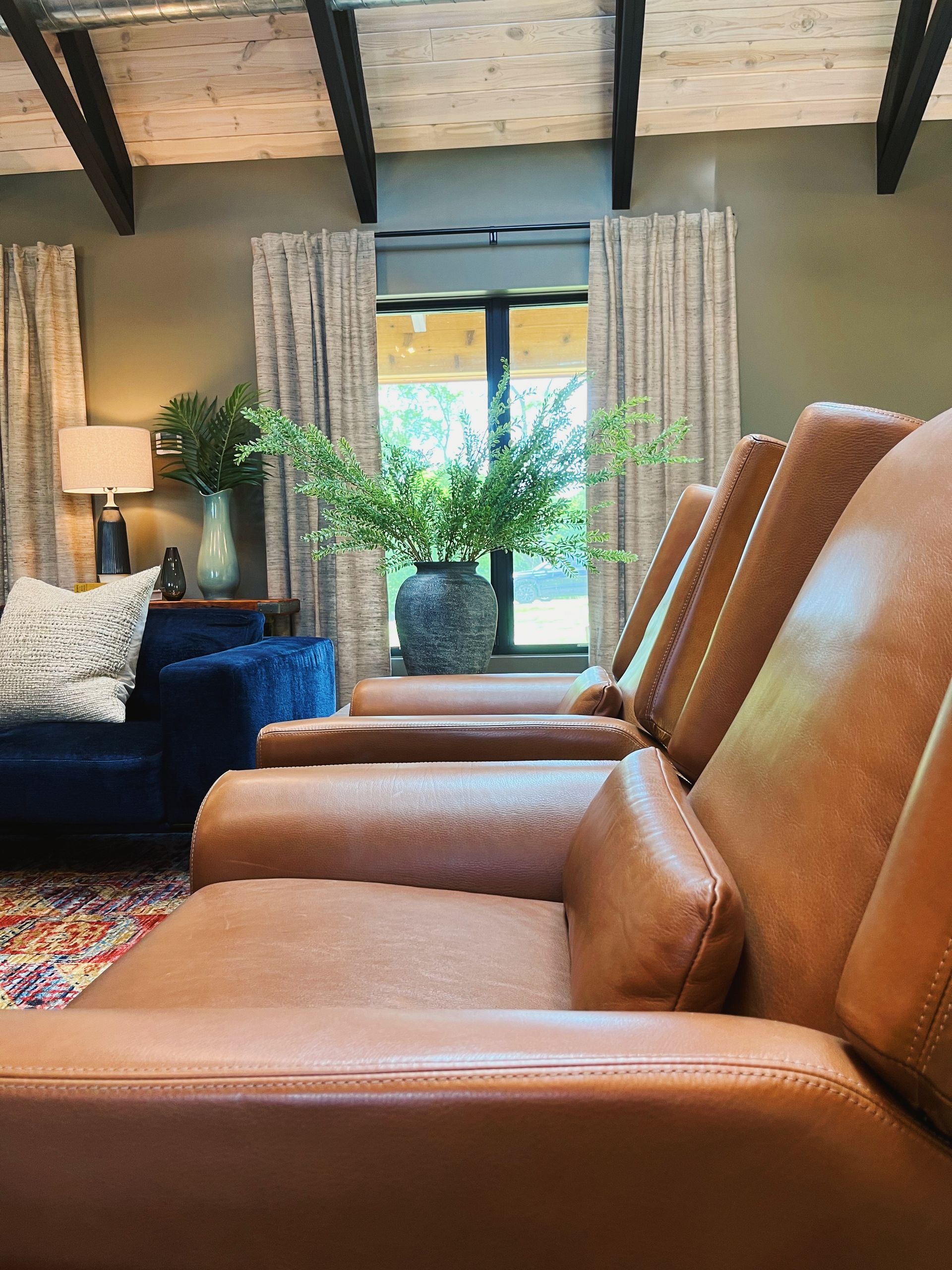 Row of tan leather recliners facing a bright window in a cozy living room