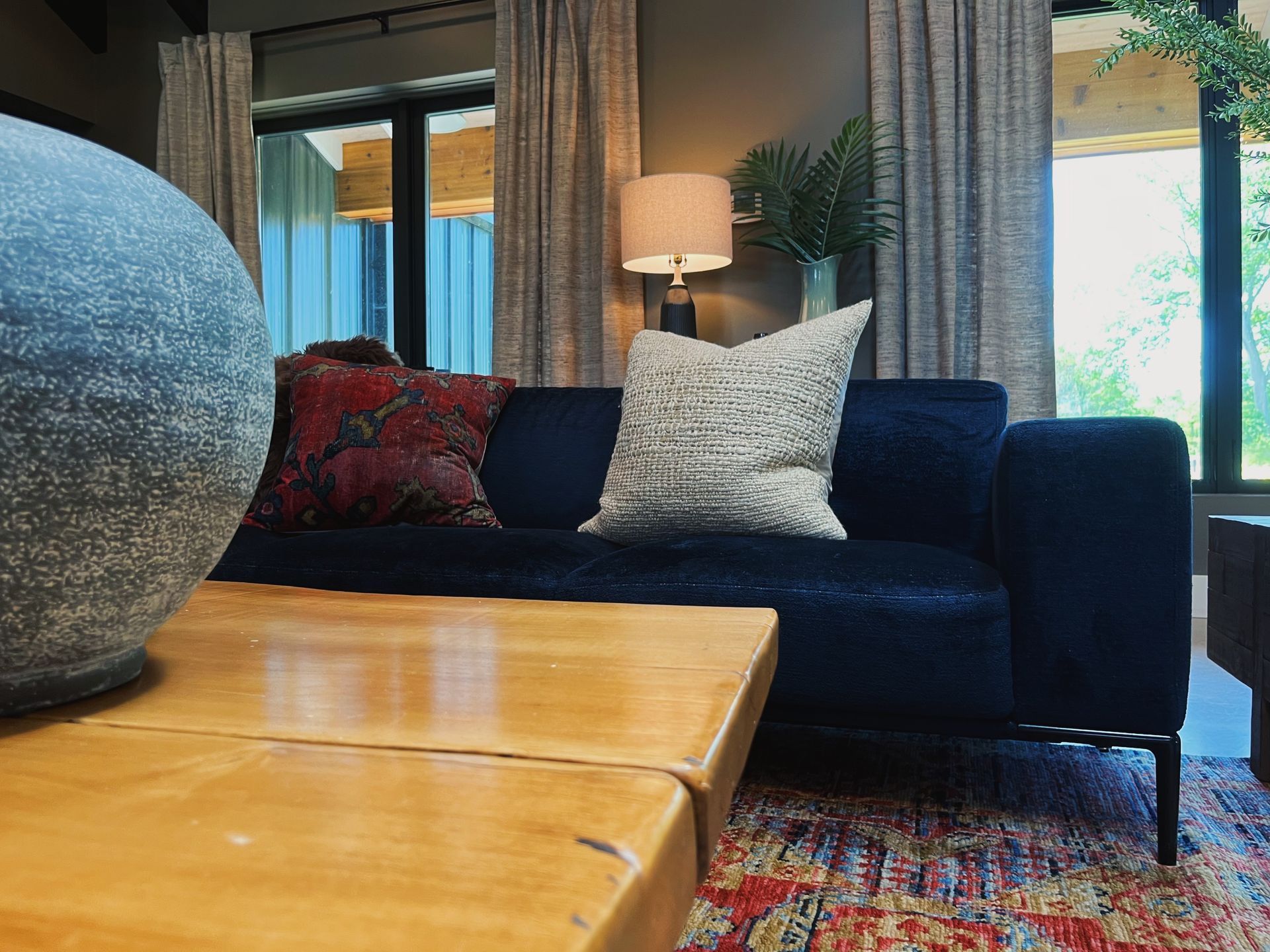 Cozy living room with dark sofa, pillows, lamp, wooden table, and large decorative vase