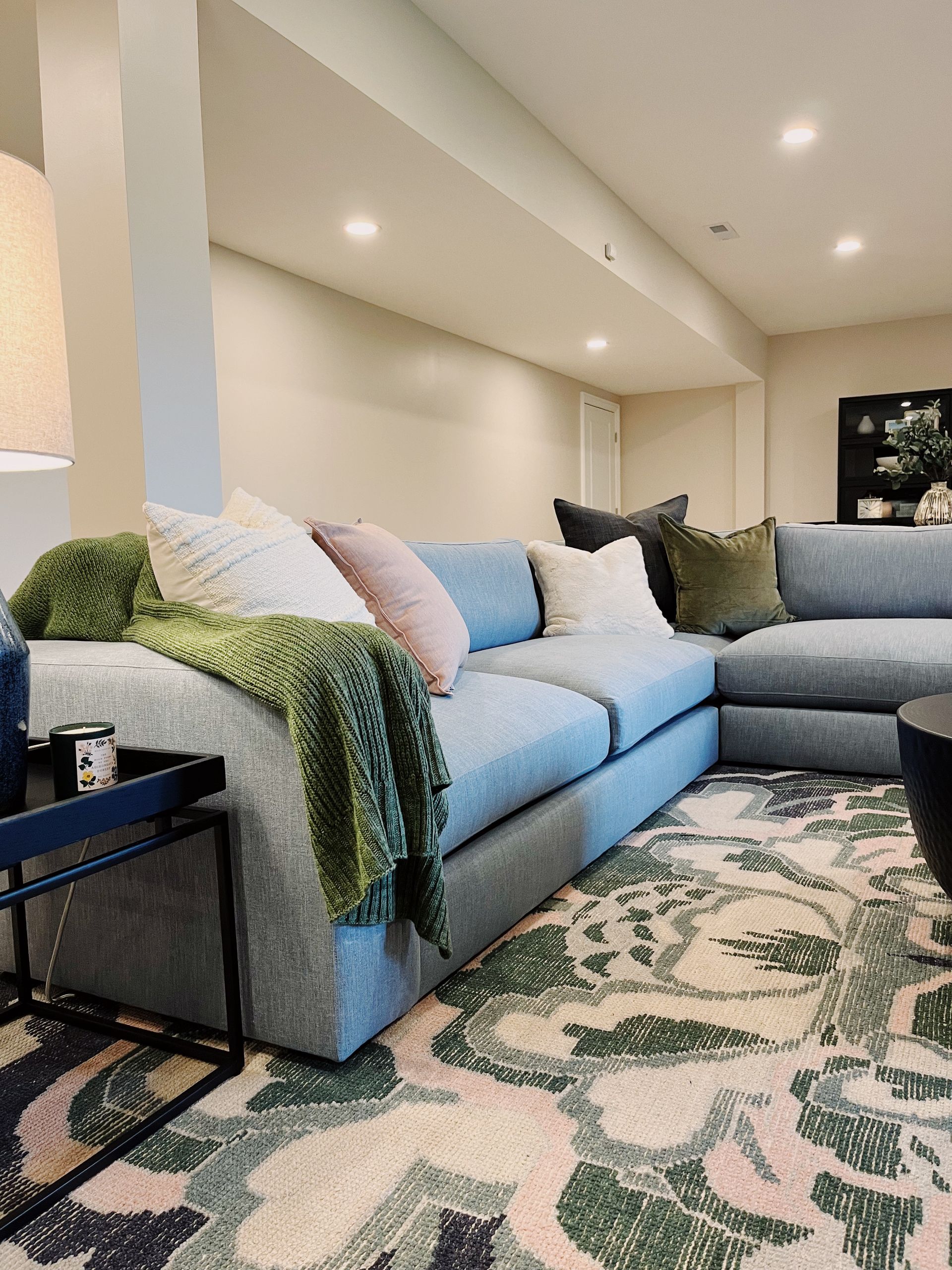 Cozy living room with gray sectional sofa, patterned rug, and warm recessed lighting