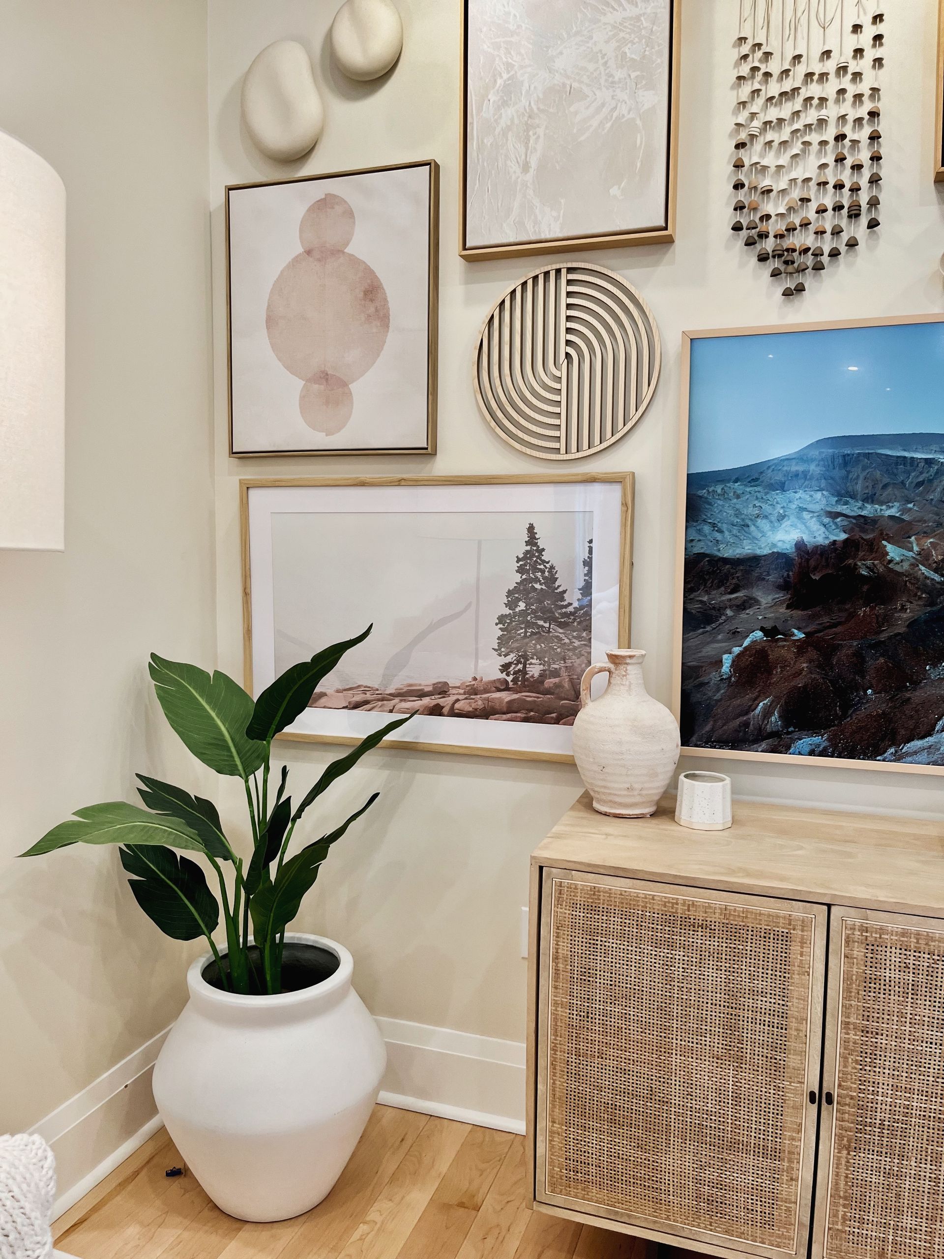Cozy corner with framed art, woven decor, a potted plant, and a TV on a rattan cabinet.