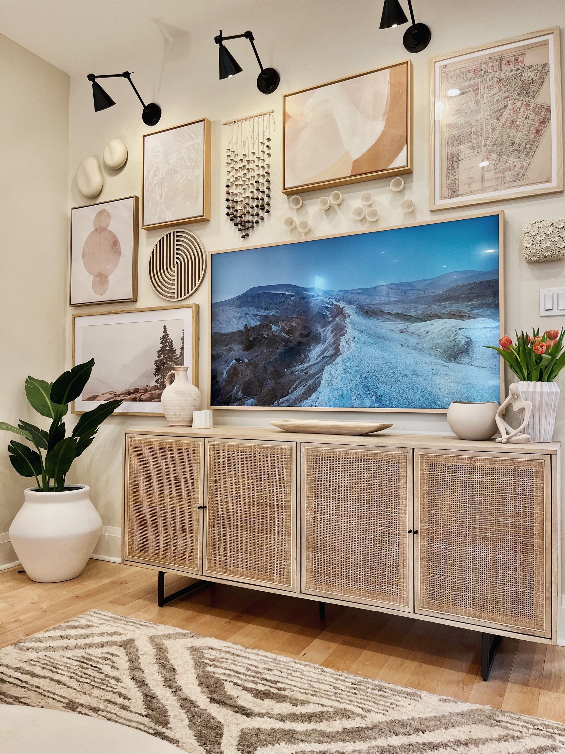 Cozy living room with woven media console, wall art, potted plants, and ocean scene on a TV.