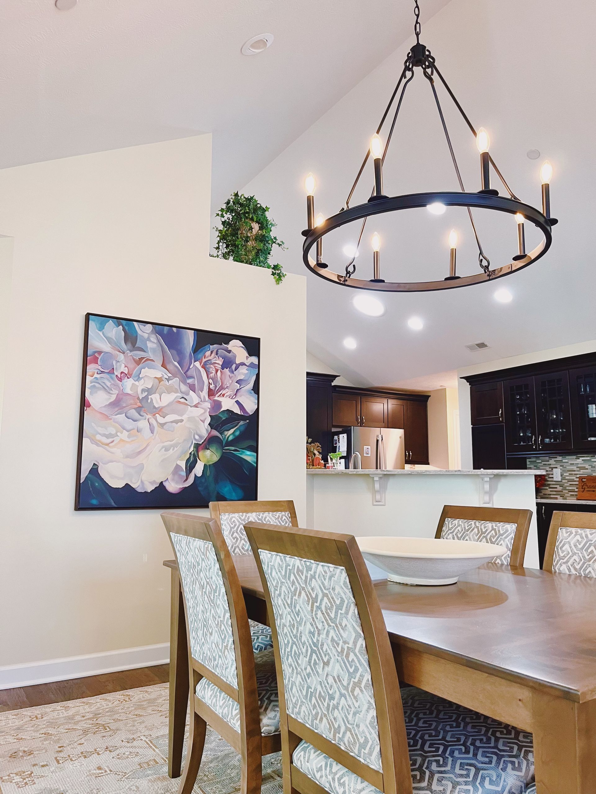Dining room with a wooden table, patterned chairs, and a black circular chandelier