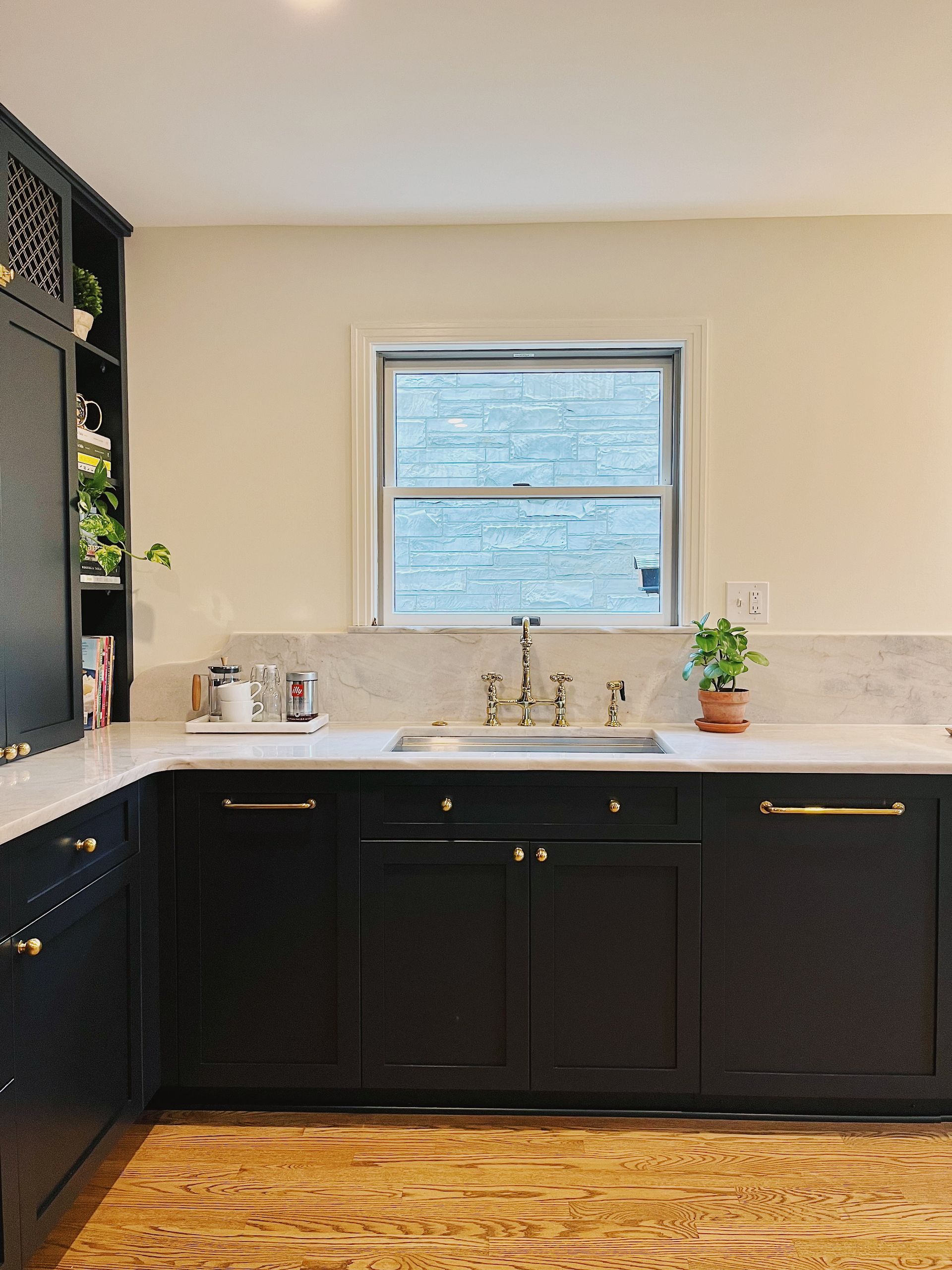 Modern kitchen with dark cabinets, white countertop, and window above the sink