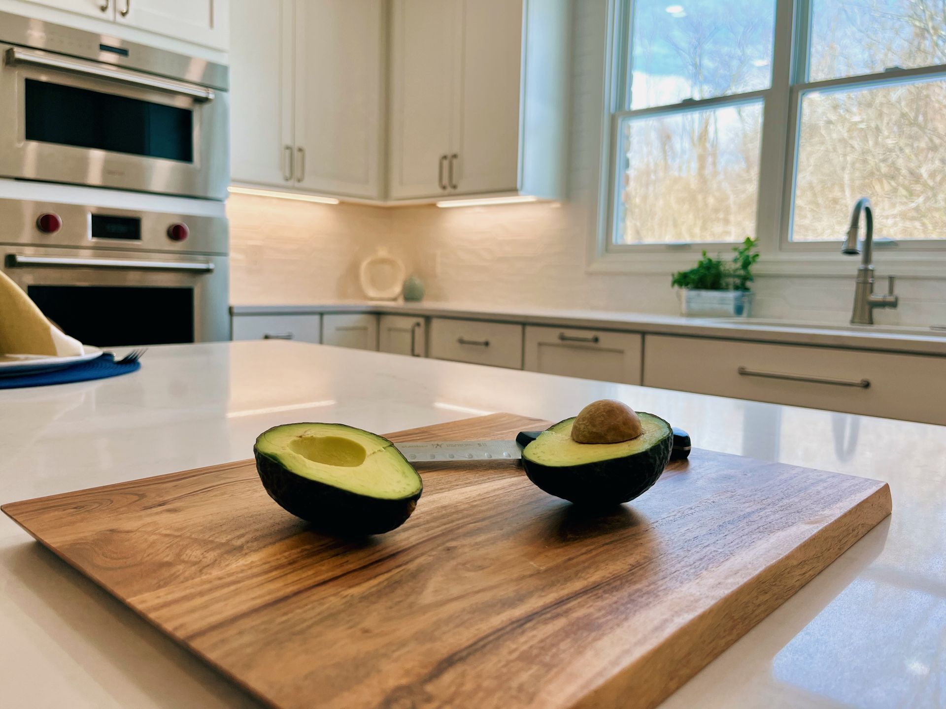Two avocado halves on a wooden cutting board in a bright, modern kitchen