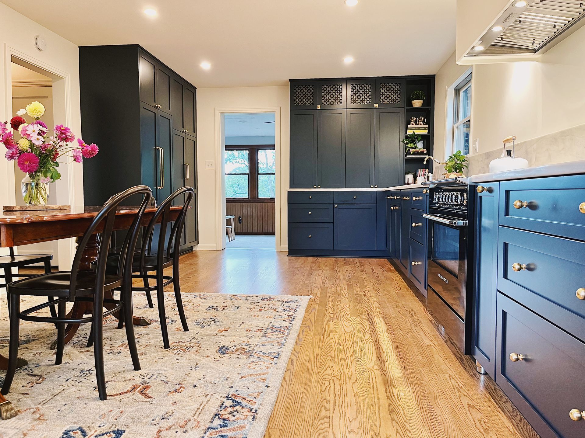 Bright kitchen with blue cabinets, wood floor, island seating, and patterned rug