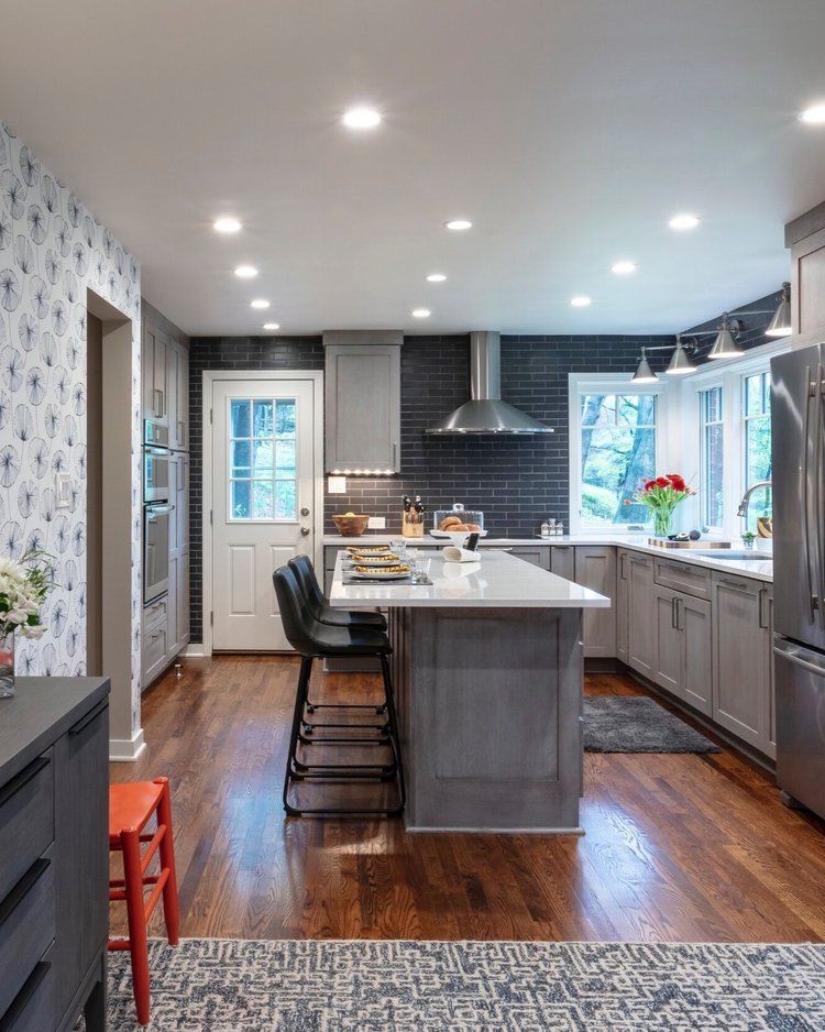 Modern kitchen with gray cabinets, white island, dark wood floors, and large windows