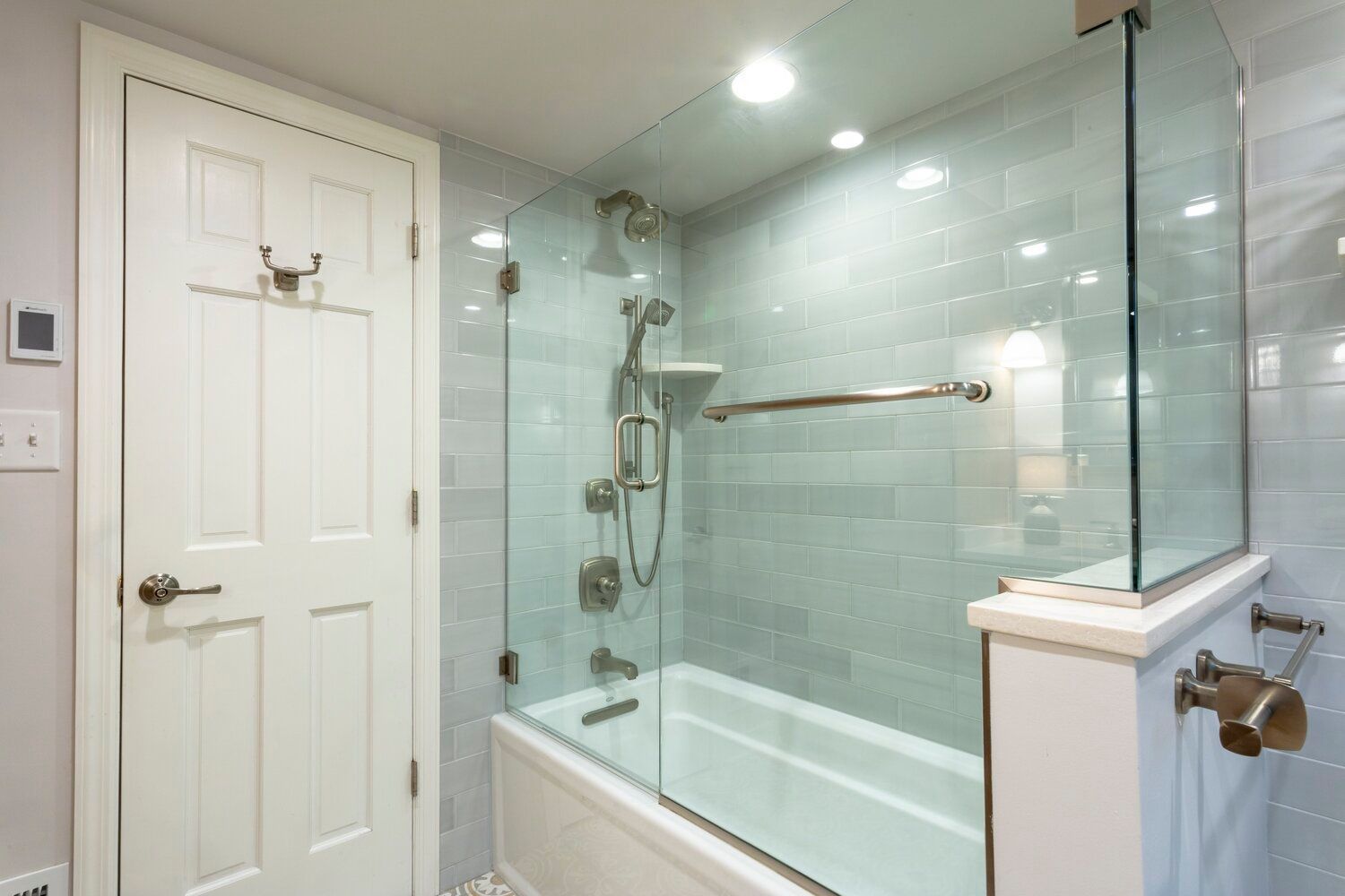 Bright bathroom with a glass-enclosed shower, white tub, and tiled walls