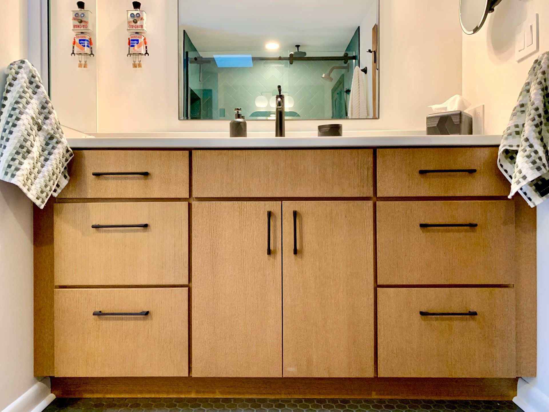 Bathroom vanity with double sink, wood cabinets, and towels hanging on both sides.