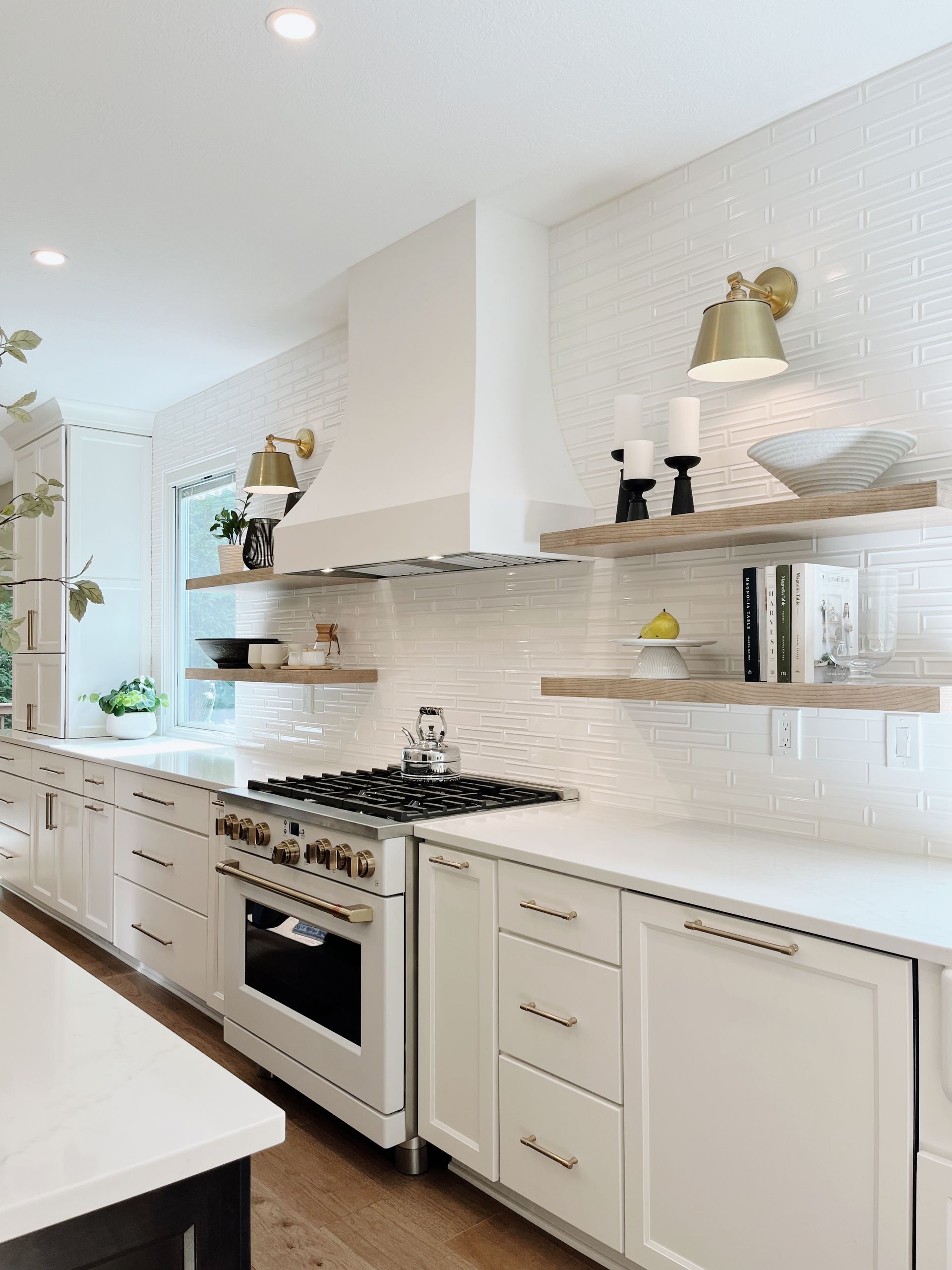 Bright white modern kitchen with gas range, open shelves, and marble-pattern backsplash.