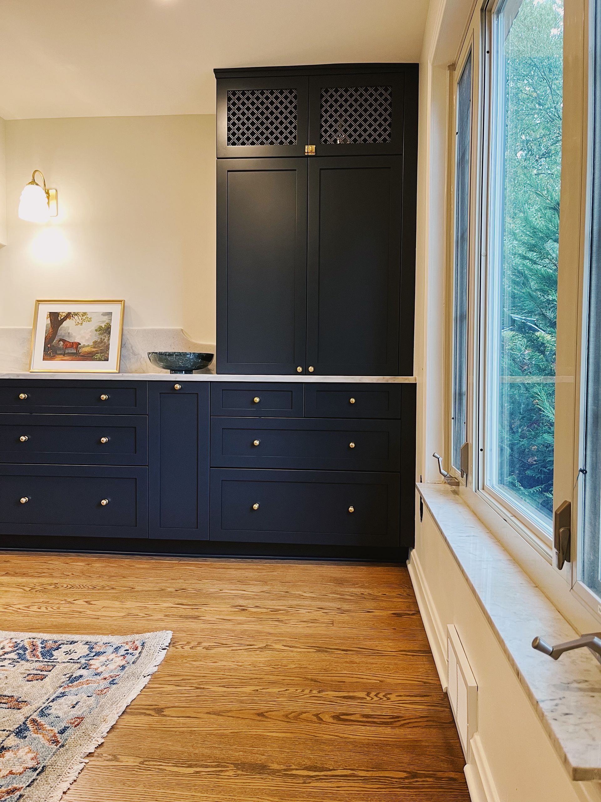 Home office with dark built-in cabinets, wood floors, and large windows overlooking trees