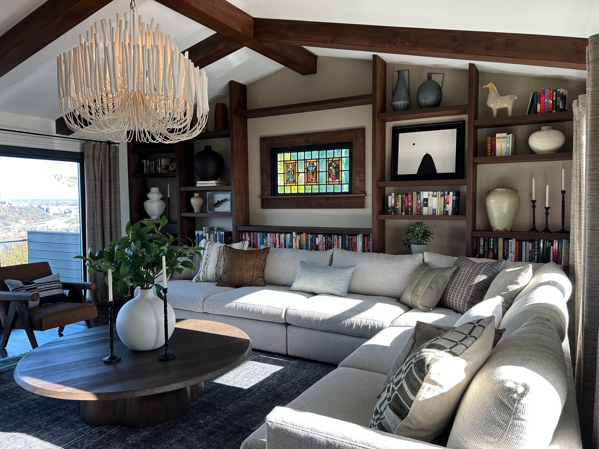 Cozy living room with a white sectional, round coffee table, wood beams, and stained-glass window accents