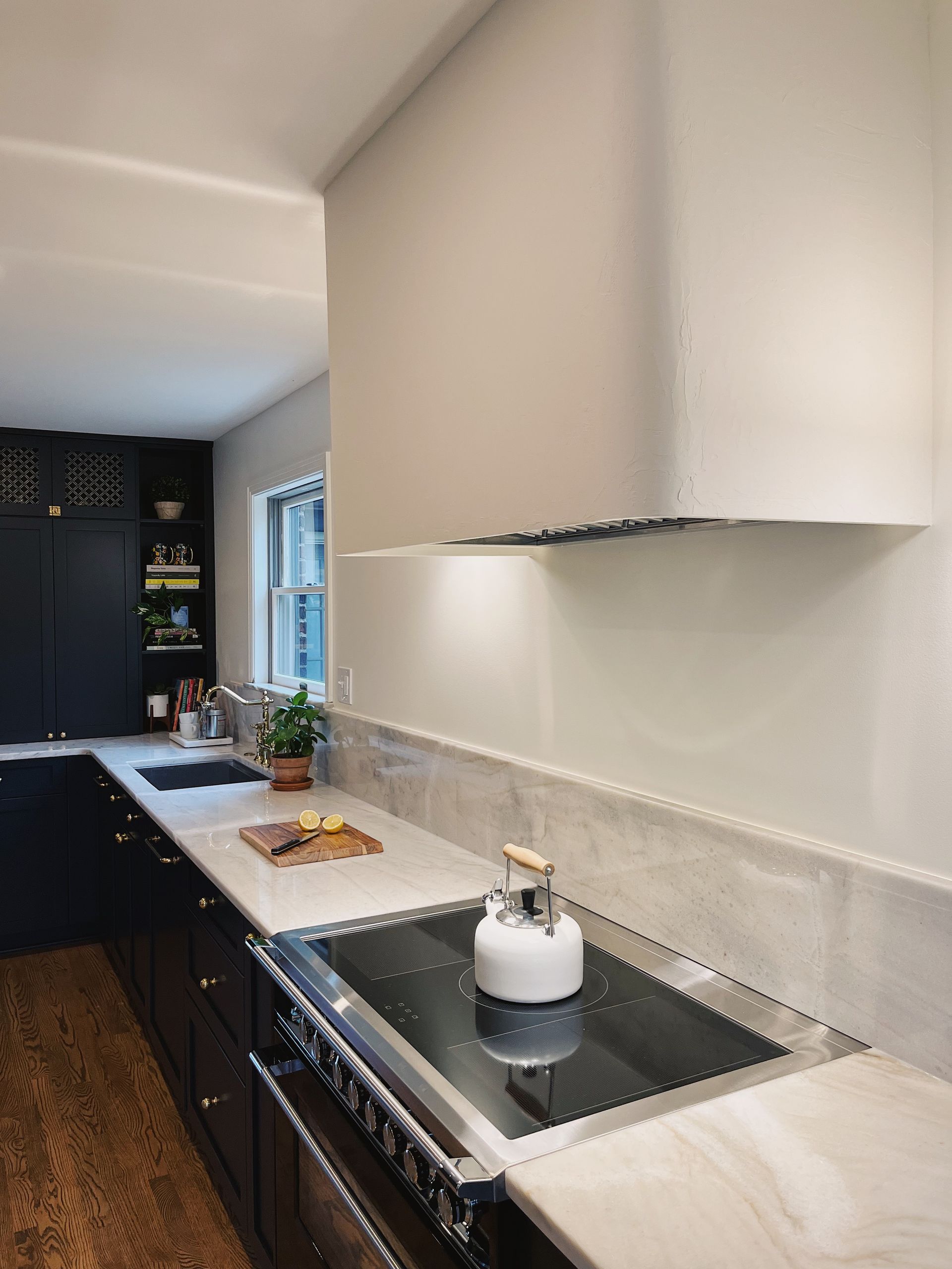 Modern kitchen with white countertops, black cabinets, and a sink in the foreground