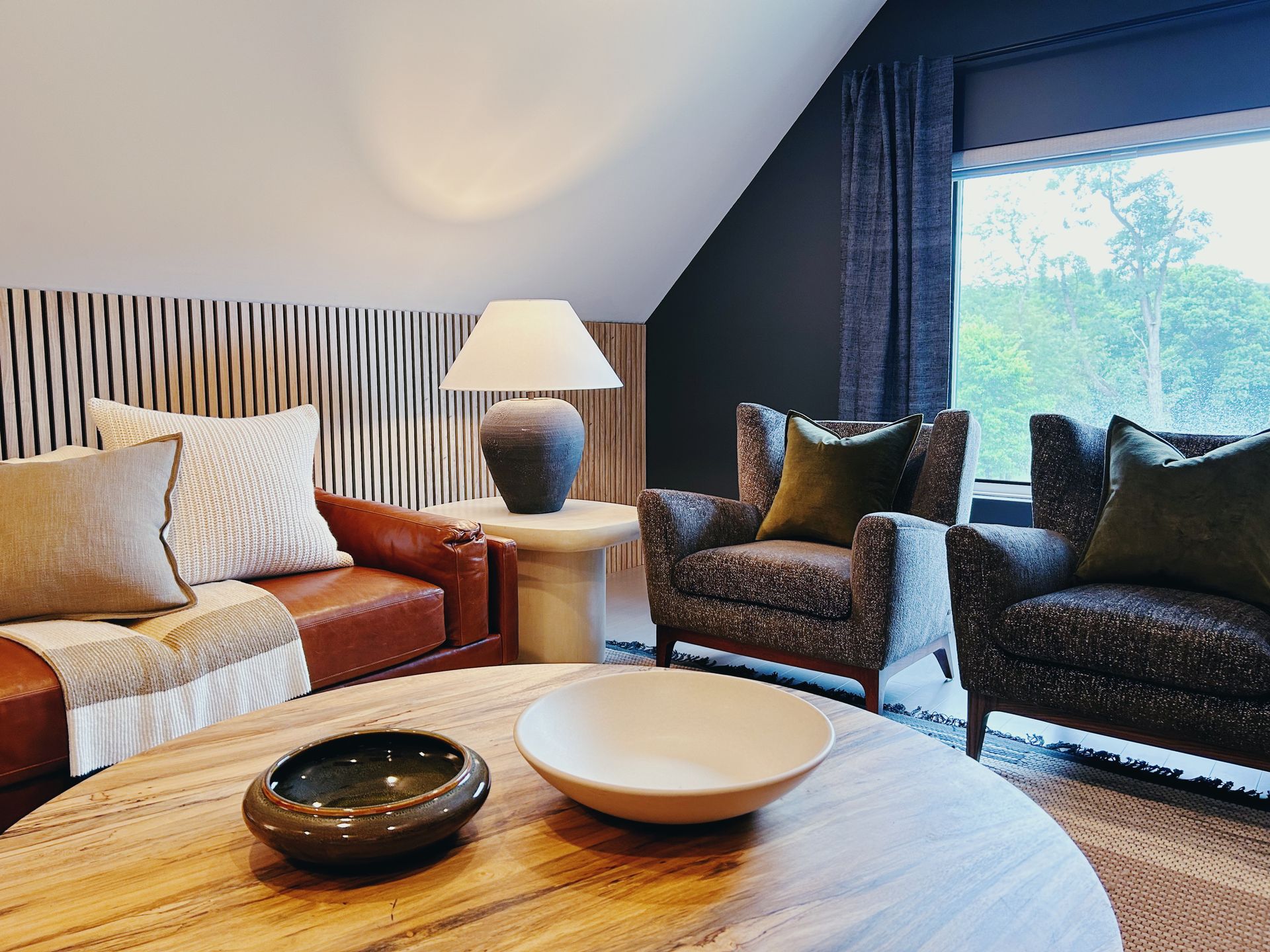 Cozy living room with sofa, armchairs, lamp, and large window with curtains