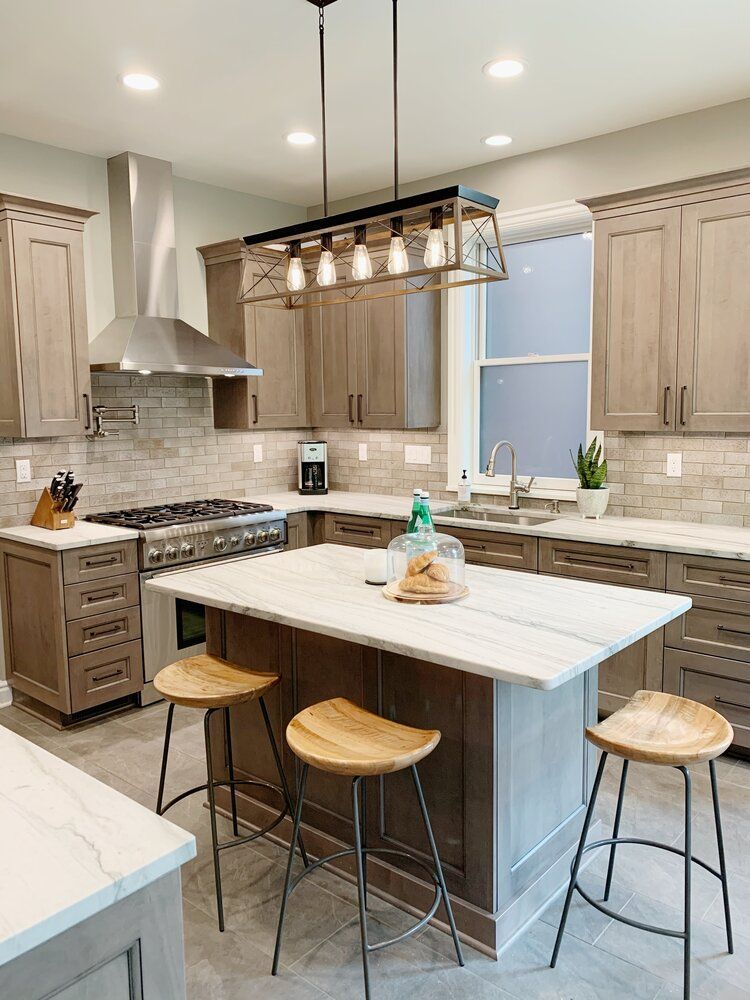 Modern kitchen with island, pendant lights, light wood cabinets, and three stools