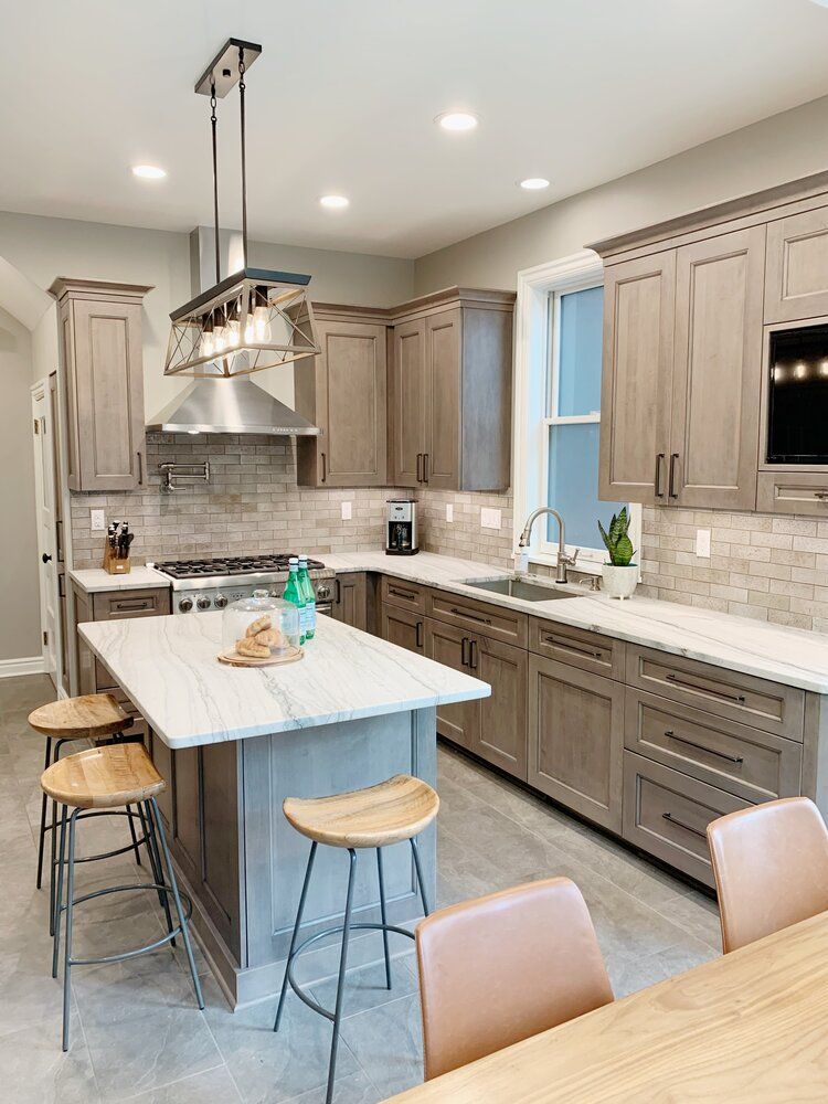 Modern kitchen with gray cabinets, white island, pendant light, and bar stools.