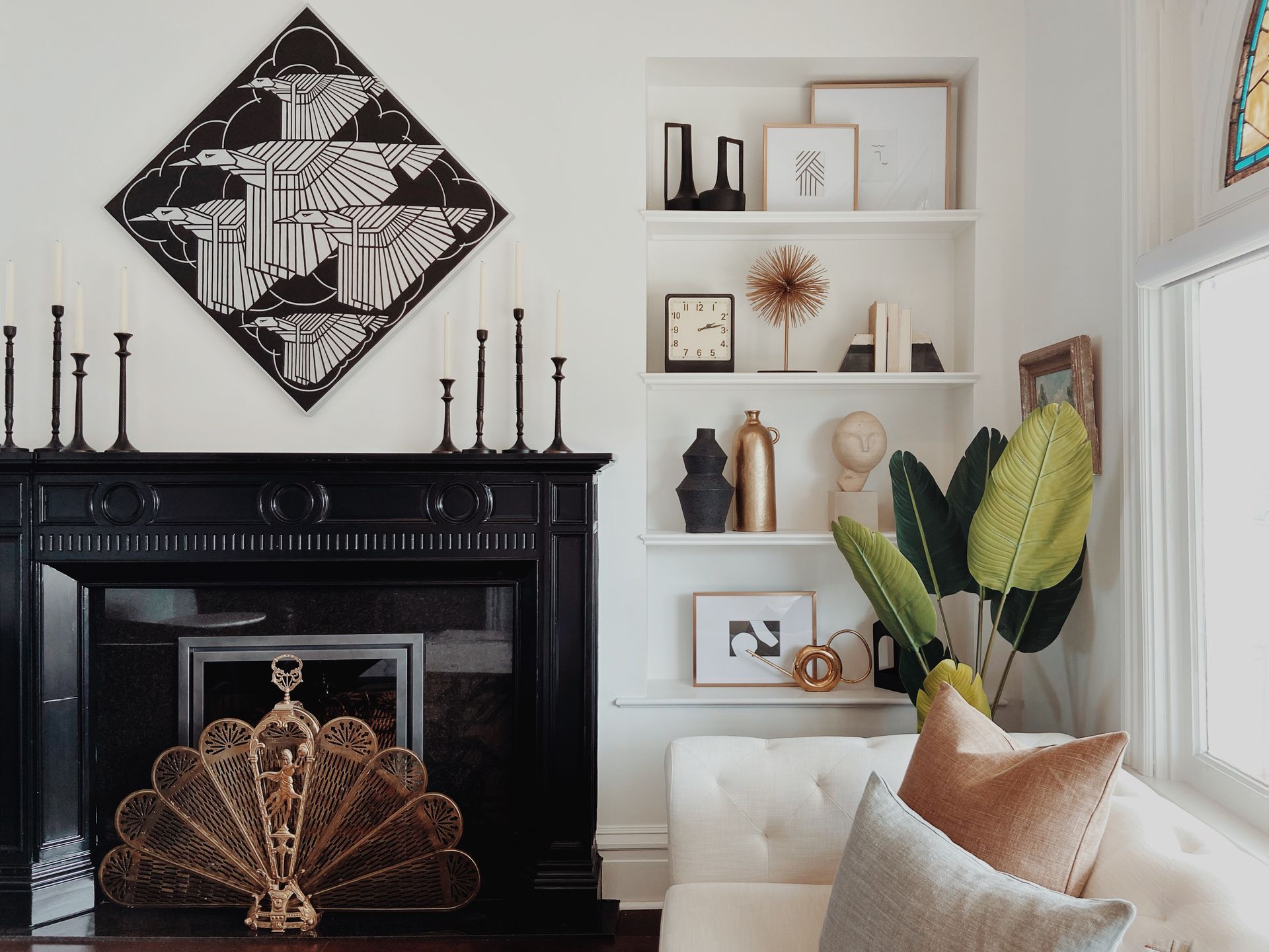 Elegant living room with black fireplace, white shelves, and a large potted plant.