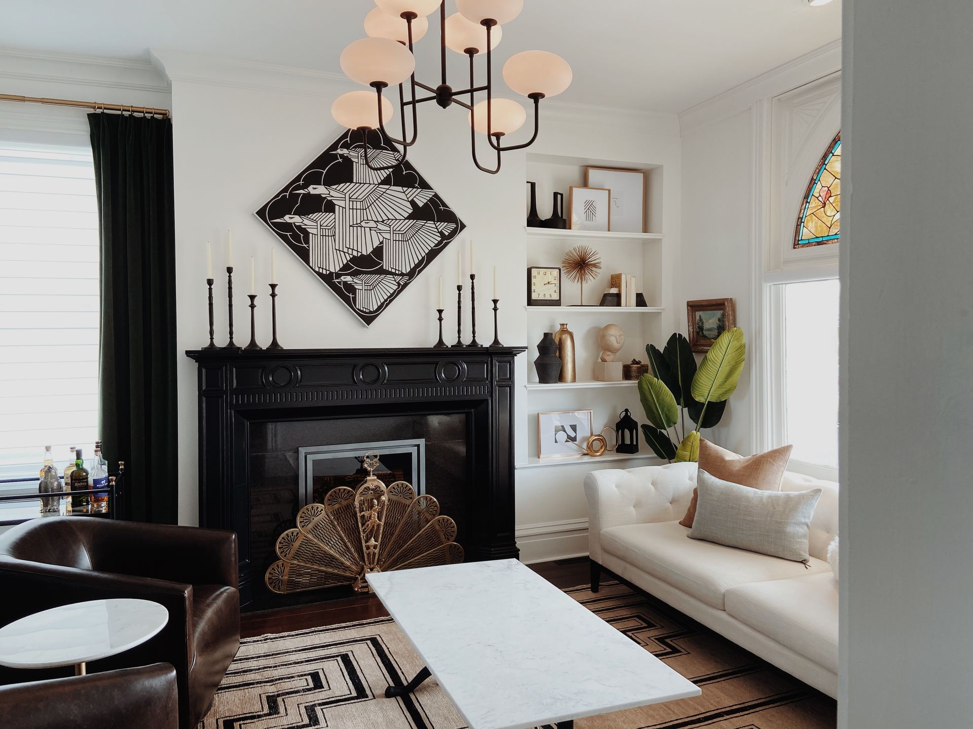 Cozy living room with black fireplace, white sofa, patterned rug, and chandelier lighting